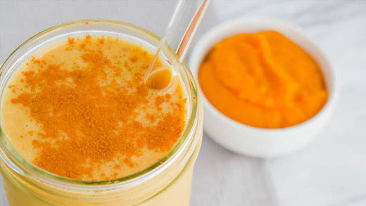 A pumpkin spice smoothie with a bowl of pumpkin puree next to it.