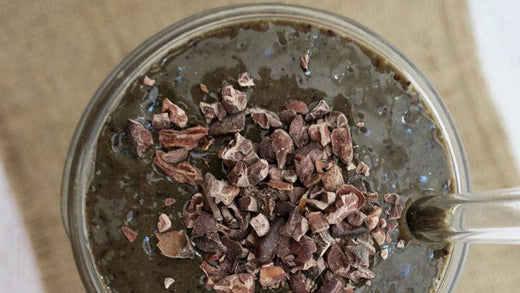 A chocolate blueberry smoothie topped with cacao nibs.