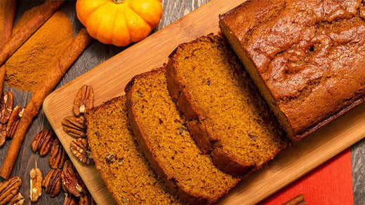 A loaf of pumpkin bread with several slices cut and laying flat on a cutting board.