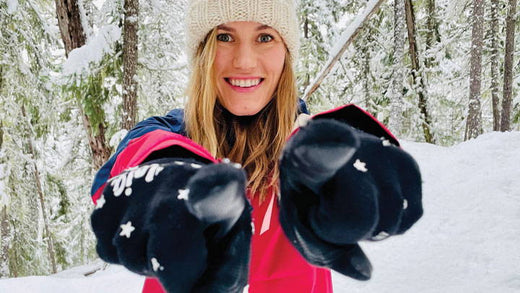 A woman in a snowy forest wearing warm clothes.