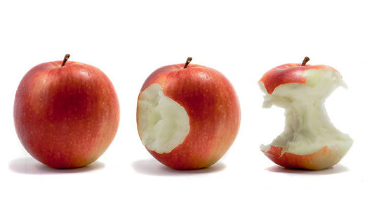 Three apples in a row, the first one is whole, the second has one bite taken out of it, and the third has been mostly eaten.