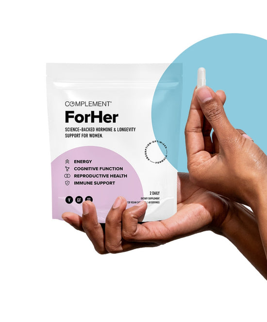 A hand holds a small capsule beside a Complement For Her supplement pack. The pack highlights benefits like energy, cognitive function, reproductive health, and immune support, tailored for women. The background features a light blue circle.
