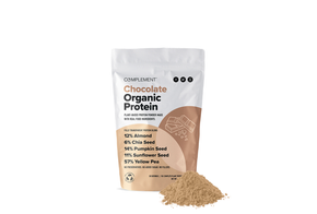 A package of Complement Chocolate Organic Protein powder is displayed against a white background. The package highlights its plant-based ingredients, including almond, chia seed, pumpkin seed, sunflower seed, and yellow pea. A small pile of the powder is in front.