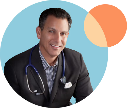 A man in a suit and checkered shirt smiles at the camera, wearing a stethoscope around his neck. The background is a circular shape with a light blue and orange design.