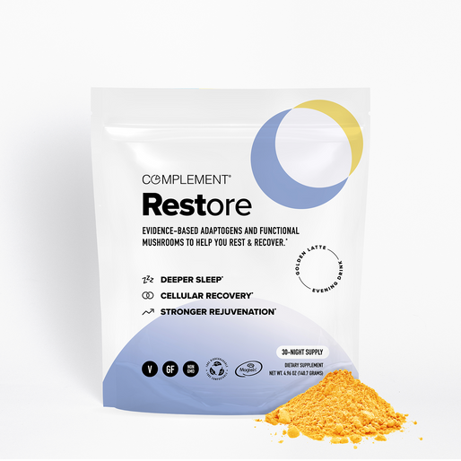 A white bag labeled Complement Restore with adaptogens and mushrooms for rest and recovery, featuring icons for deeper sleep, cellular recovery, and stronger rejuvenation. Orange powder is shown spilled in front.