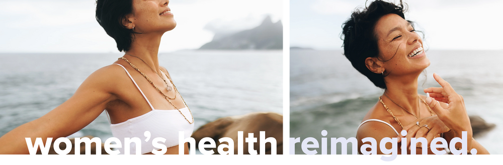 A woman in a white top stands by the ocean, smiling and looking content. The image is split into two sections, with the text womens health reimagined at the bottom. The background shows a serene, cloudy shoreline.