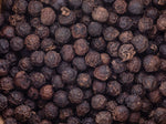 Close-up view of many whole black peppercorns, showing their round, wrinkled texture and dark brown to black color.