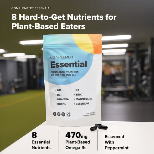 A bag of COMPLEMENT® Plant‑Based Essentials Stack by Complement sits on a gym table. The packaging highlights B12, D3, DHA/EPA, zinc, magnesium, iodine, and selenium. Three capsules are placed next to the bag.