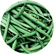 A pile of fresh green beans, with slender and elongated shapes, overlapping each other. The beans have a vibrant green color, with some small brown spots and a few stems still attached.