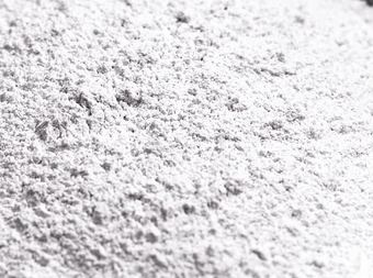 A close-up view of a fine white powder with a slightly rough, uneven texture, spread out in an even layer.