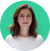 A woman with shoulder-length brown hair is wearing a white top and standing against a solid green background. She has a neutral expression and is centered in the image.
