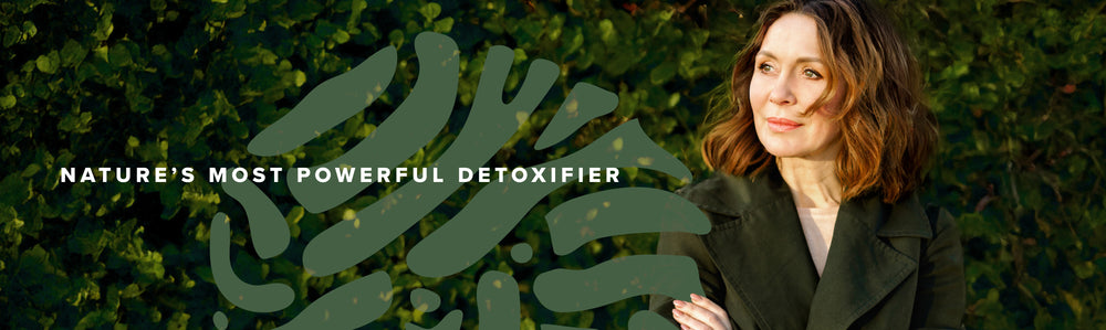 A woman with shoulder-length brown hair stands outdoors in front of green foliage, wearing a dark coat. Text overlaid reads “Nature’s Most Powerful Detoxifier” with abstract green shapes in the background.