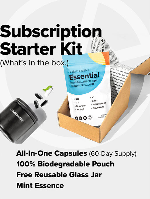 Open cardboard box with a pouch labeled COMPLEMENT® Essential by Complement, a black reusable glass jar, mint leaves, and plant-based capsules. Features include 60-day supply, biodegradable pouch, reusable jar, mint essence, and plant-based multivitamin.