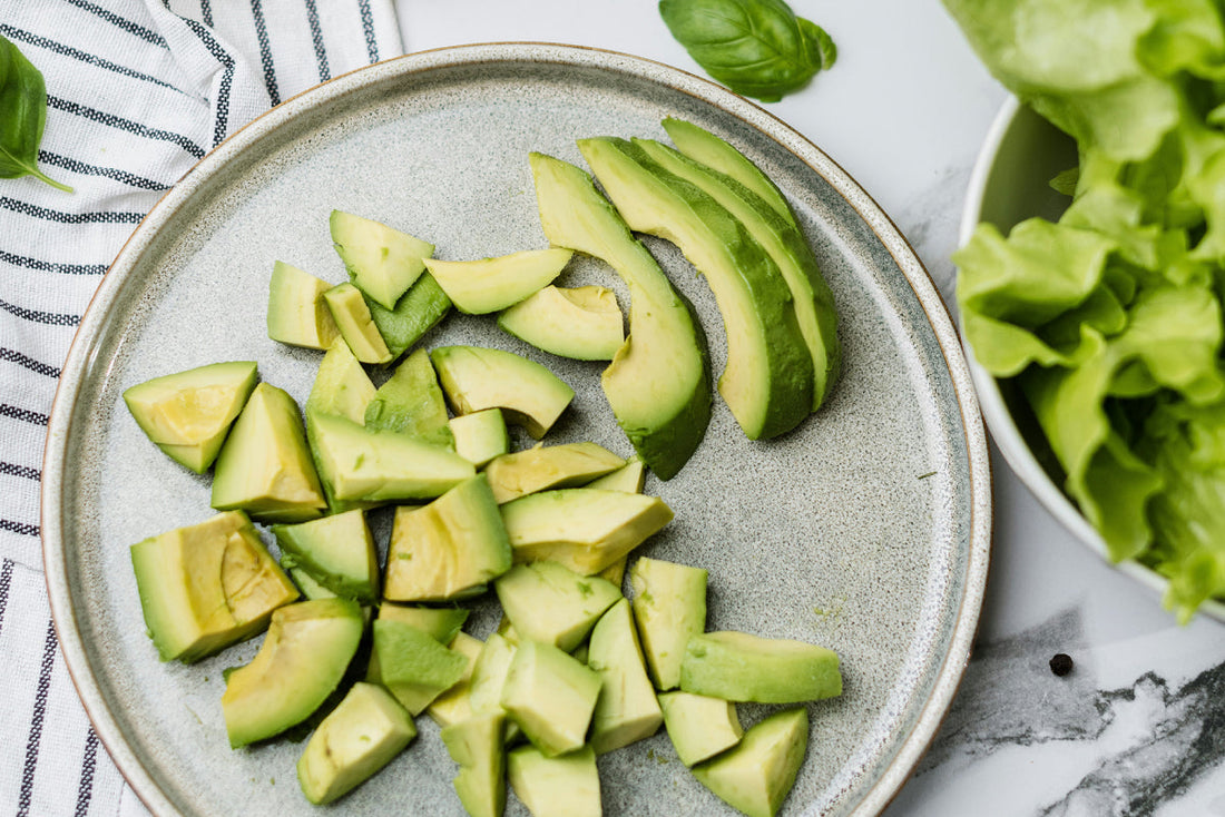 plate of diced avocados next to a bowl of green lettuce.