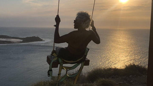A person on a swing overlooking the ocean.