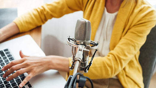 A person sitting at a computer with a mic in front of them.