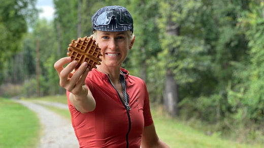 A woman holding up a small maple-infused waffle.