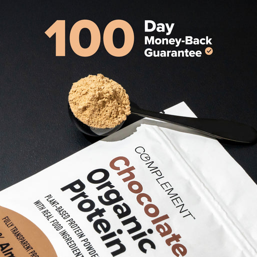 A spoonful of chocolate protein powder rests on a black surface beside a Complement Chocolate Organic Protein pouch. Text reads “100 Day Money-Back Guarantee.”.