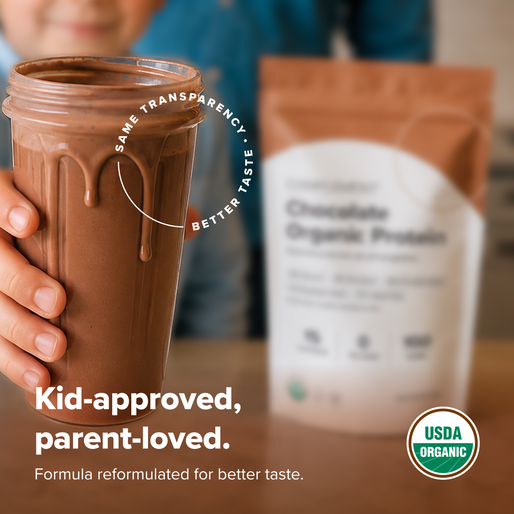 A hand holds a glass of chocolate protein shake with a package of Chocolate Organic Protein powder blurred in the background. Text on image reads: “Kid-approved, parent-loved. USDA Organic.”.