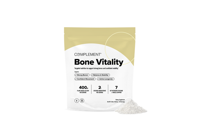 A white and yellow package labeled Complement Bone Vitality stands upright on a white background. In front of the package, a small pile of white powder is visible. The packaging highlights key benefits and ingredients.