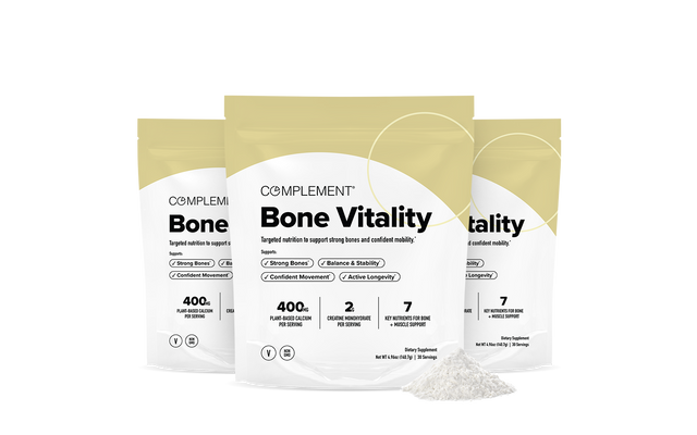 Three beige and white pouches labeled Complement Bone Vitality are displayed, with bone health benefits listed on the front. A small pile of white powder is in front of the packages against a plain background.