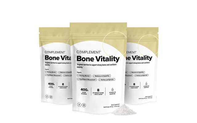 Three bags of Complement Bone Vitality supplement stand upright with a small pile of powder in front. The packaging is beige and white, listing benefits like strong bones and 400g per bag. The background is plain white.