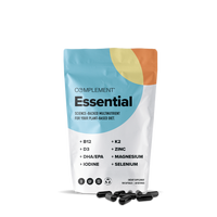 A white, colorful resealable pouch labeled Complement® Essential (Plant Based) multivitamin from Complement stands upright with several black omega-3 capsules scattered in front on a white background.