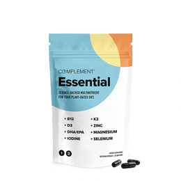 A white and multicolored resealable pouch labeled Complement Essential with a list of nutrients like B12, D3, DHA/EPA, iodine, K2, zinc, magnesium, and selenium. Three black capsules are placed beside the pouch.