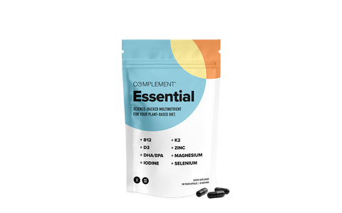 A white and colorful resealable pouch labeled Complement Essential with science-backed multinutrient for a plant-based diet, next to three black capsules. Key nutrients listed include B12, D3, DHA/EPA, Iodine, K2, Zinc, Magnesium, and Selenium.