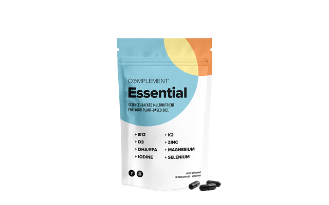A white and colorful resealable pouch labeled Complement Essential with science-backed multinutrient for a plant-based diet, next to three black capsules. Key nutrients listed include B12, D3, DHA/EPA, Iodine, K2, Zinc, Magnesium, and Selenium.