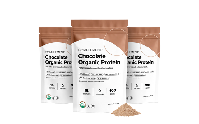 Three bags of Complement Chocolate Organic Protein powder with a pile of brown protein powder in front.