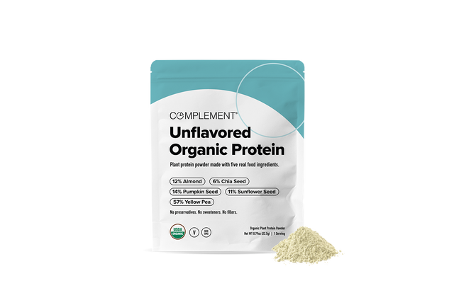 A teal and white pouch labeled Complement Unflavored Organic Protein stands next to a small pile of beige protein powder. The packaging lists ingredients like almond, pumpkin seed, chia seed, sunflower seed, and yellow pea.