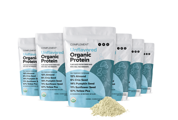 Six standing bags of Complement Unflavored Organic Protein powder with a pile of protein powder in front. The packaging highlights plant-based protein sources like almond, chia, pumpkin, sunflower, and yellow pea.