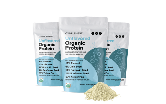 Three bags of Complement Unflavored Organic Protein powder are displayed, featuring ingredient percentages on the packaging. A small mound of light-colored protein powder is in front of the bags on a white background.