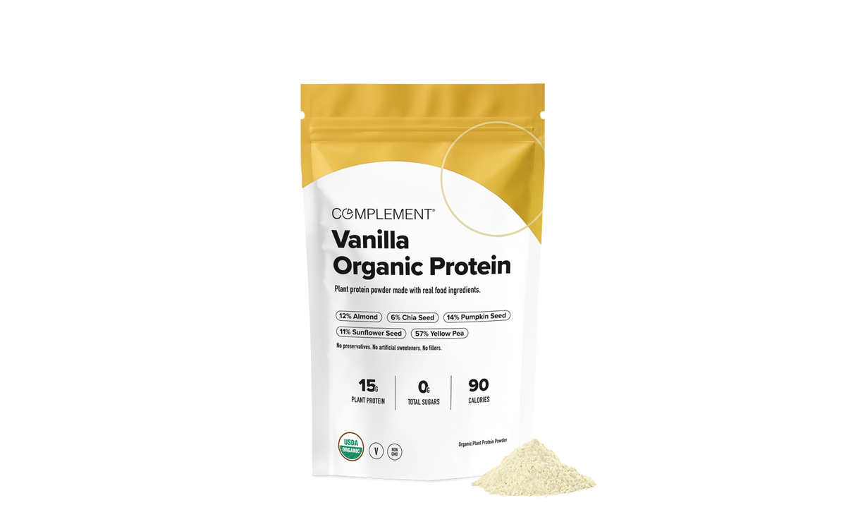 A pouch of Complement Vanilla Organic Protein powder with a small pile of the powder in front of it.