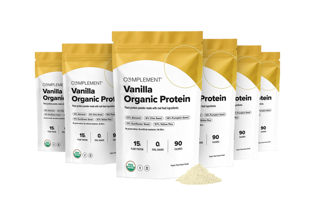 Six pouches of Complement vanilla organic protein powder arranged in a semi-circle behind a small pile of protein powder.