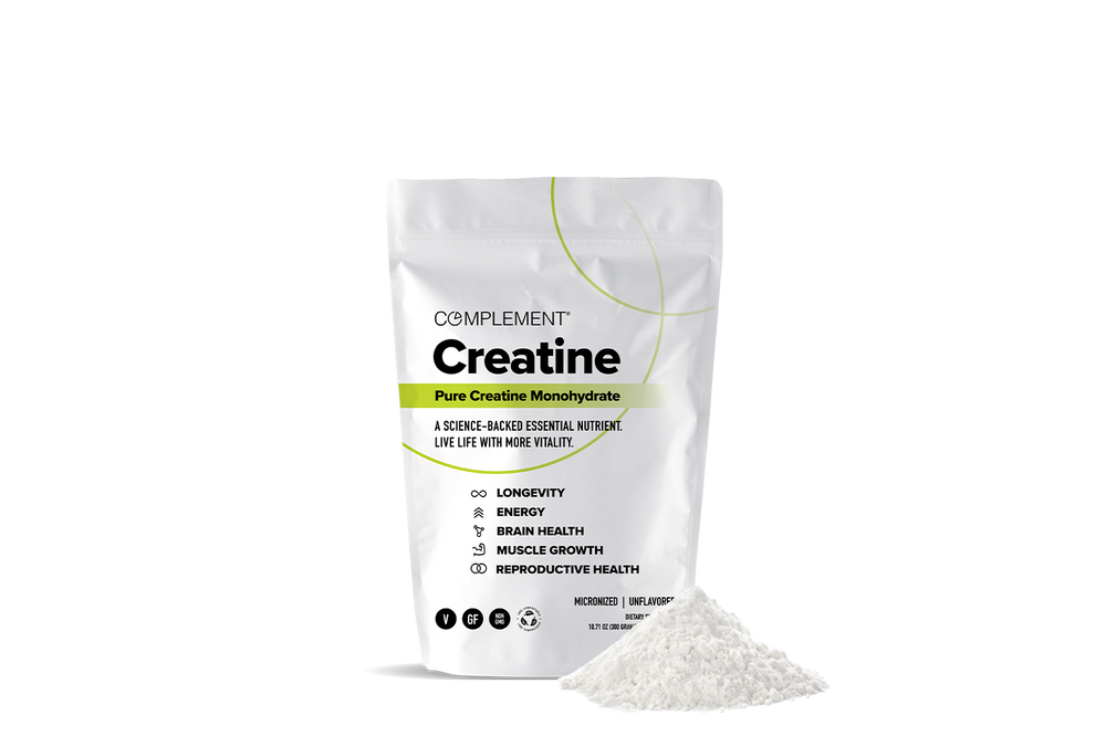 A white pouch labeled Complement Creatine stands upright next to a small pile of white creatine powder. The packaging highlights benefits like longevity, energy, brain health, muscle growth, and reproductive health.