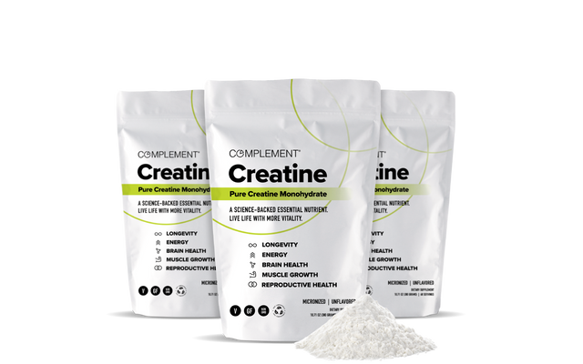 Three white bags of Complement Creatine Monohydrate are displayed behind a small mound of creatine powder. The packaging highlights benefits like longevity, energy, brain health, muscle growth, and reproductive health.