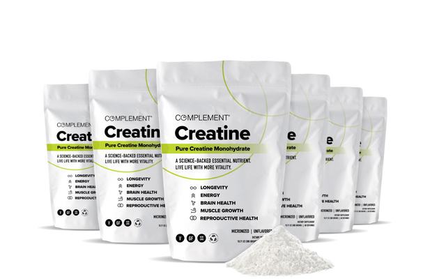 Six white pouches of Complement Creatine Pure Creatine Monohydrate powder are arranged in a row, with a heap of white powder in front. The packaging highlights benefits like energy, muscle growth, and brain health.