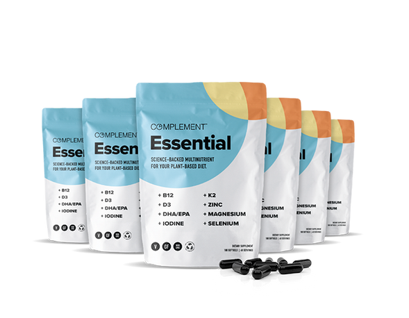 Six standing Complement Essential supplement pouches feature a modern design with colorful geometric shapes. The pouches highlight nutrients like B12, D3, DHA/EPA, iodine, K2, zinc, magnesium, and selenium. Black capsules are scattered in front.