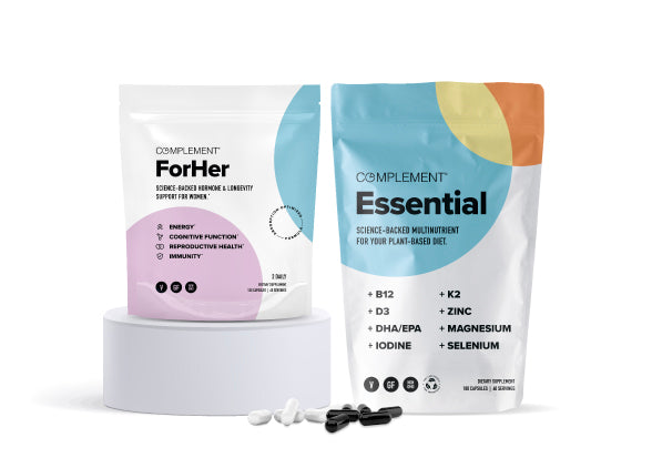 Bags of dietary supplements on display. One is labeled For Her, designed for energy, hormone support, and immunity. The other is labeled Essential, a multivitamin with B12, K2, zinc, and more, against a minimalist backdrop.