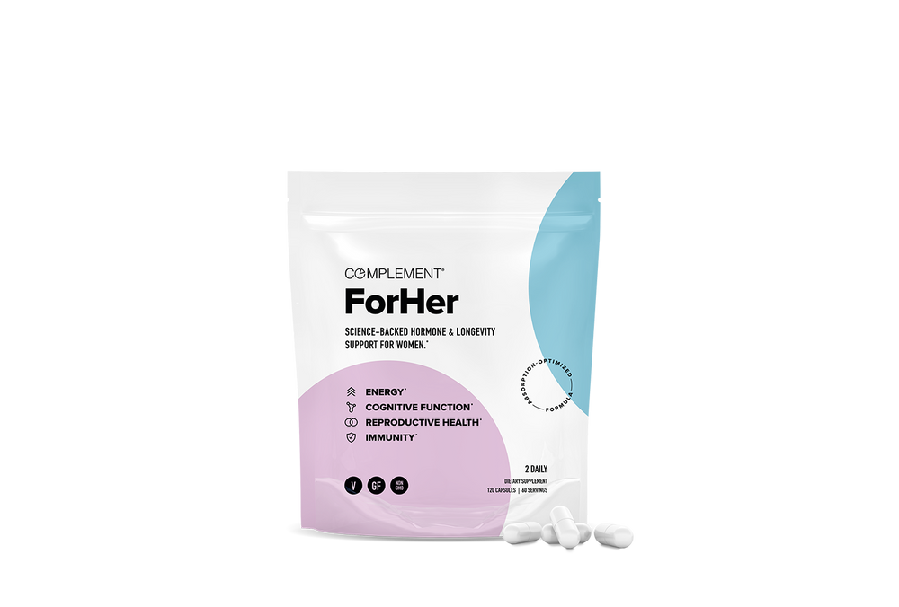 A white and pastel-colored pouch labeled Complement ForHer sits upright with a few white capsules beside it. The packaging highlights support for energy, cognitive function, reproductive health, and immunity.
