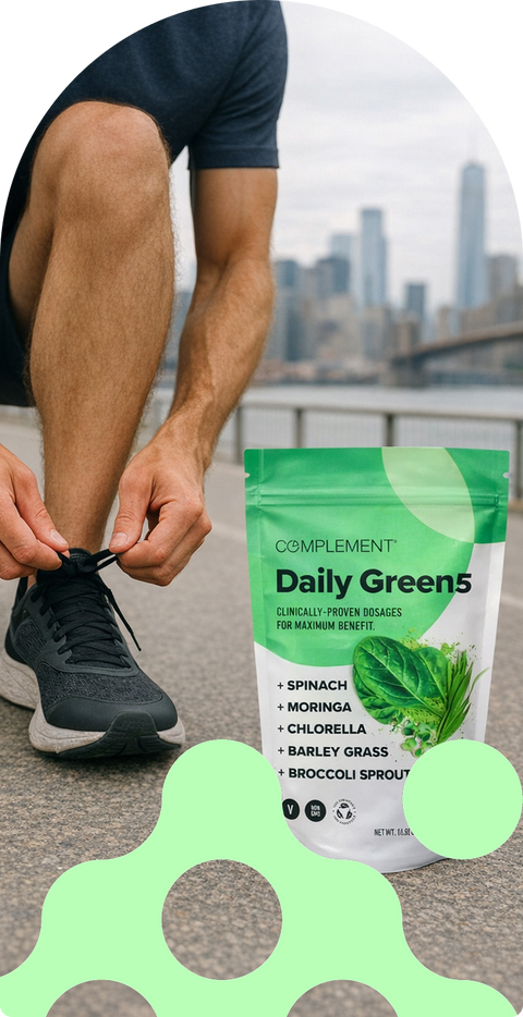 A person in athletic wear ties their shoe outdoors near a city skyline. In the foreground, a green bag labeled Complement Daily Green5 lists ingredients like spinach and moringa. Green abstract shapes overlay the image.