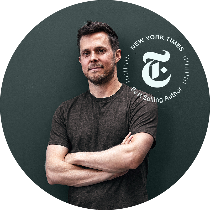 A man with short dark hair and a trimmed beard, wearing a dark t-shirt, stands with arms crossed in front of a dark green background. Next to him is a New York Times Best Selling Author badge.