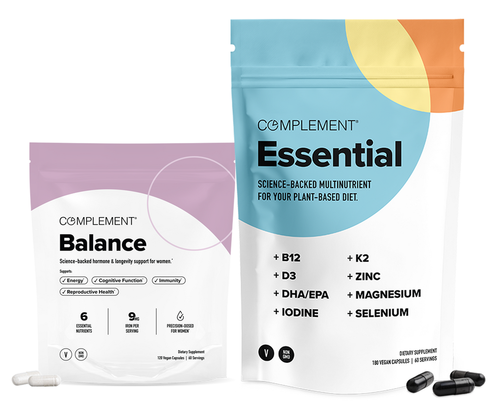Two supplement packages: one labeled Balance in purple and white, and a larger one labeled Essential in blue and white, both from Complement, with capsules displayed in front of each package.