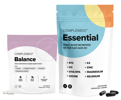 Two supplement packages: one labeled Balance in purple and white, and a larger one labeled Essential in blue and white, both from Complement, with capsules displayed in front of each package.
