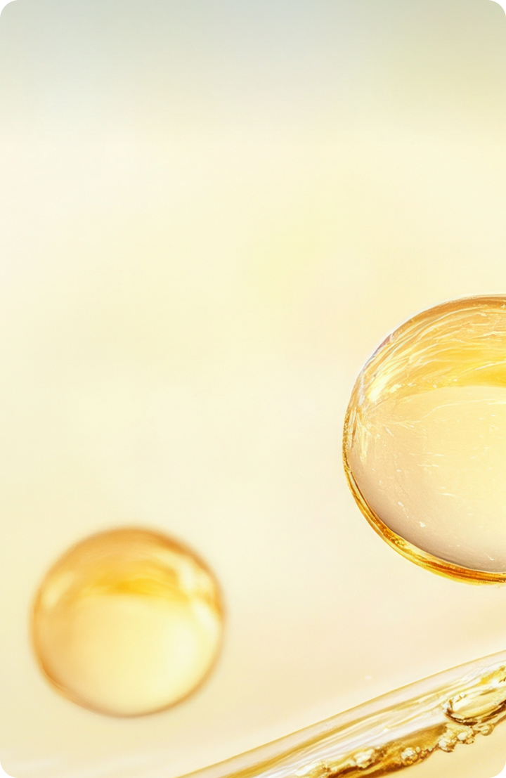 Two golden-yellow translucent spheres floating against a soft, light background, with a curved, glossy surface at the bottom right.