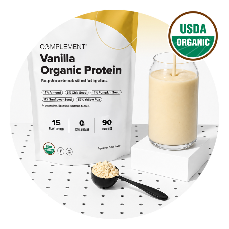 A bag of Complement Vanilla Organic Protein powder, a glass of smoothie, and a black scoop with powder sit on a white surface. A USDA Organic badge is shown in the top right corner.