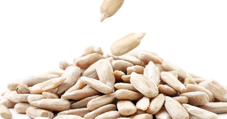A close-up of shelled sunflower seeds piled together, with a few seeds falling from above, set against a white background.
