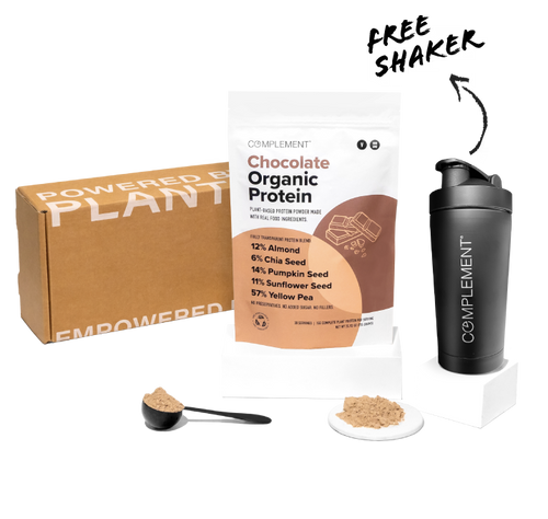 A brown box labeled Powered by Plants, a bag of chocolate organic protein powder with ingredients listed, a black shaker bottle with a logo, and a scoop with protein powder are displayed against a white background.